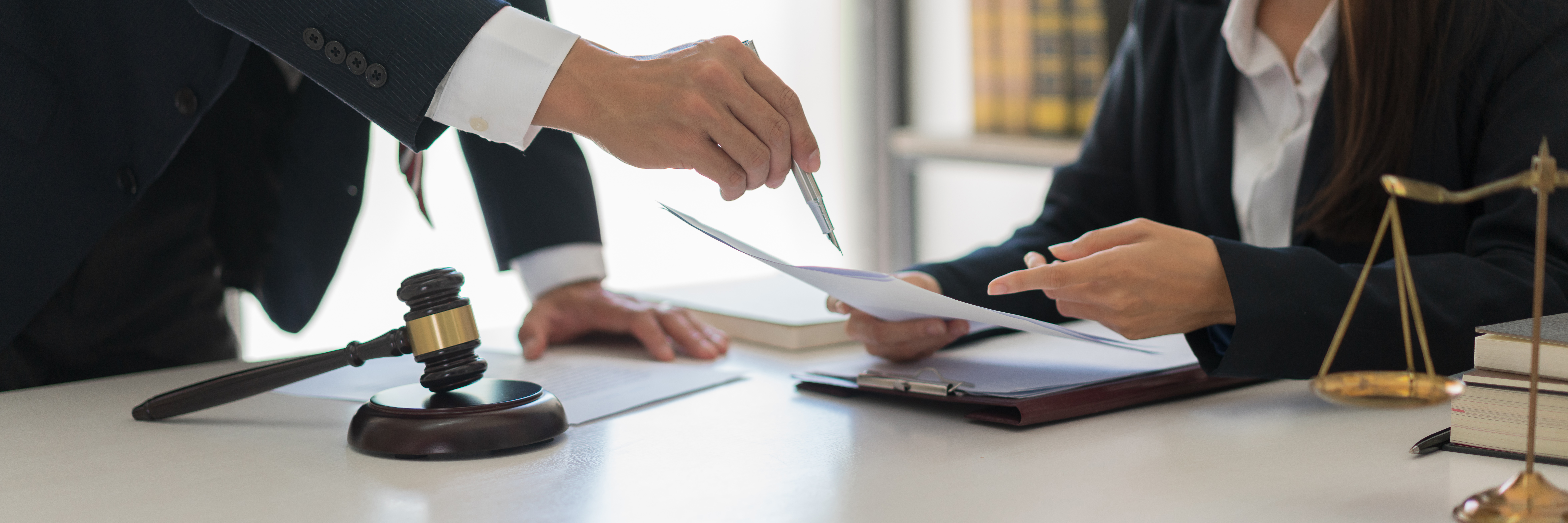 Lawyers reviewing documents related to the Employment Subsidy Decree in an office setting, with gavel and scales of justice on the table.